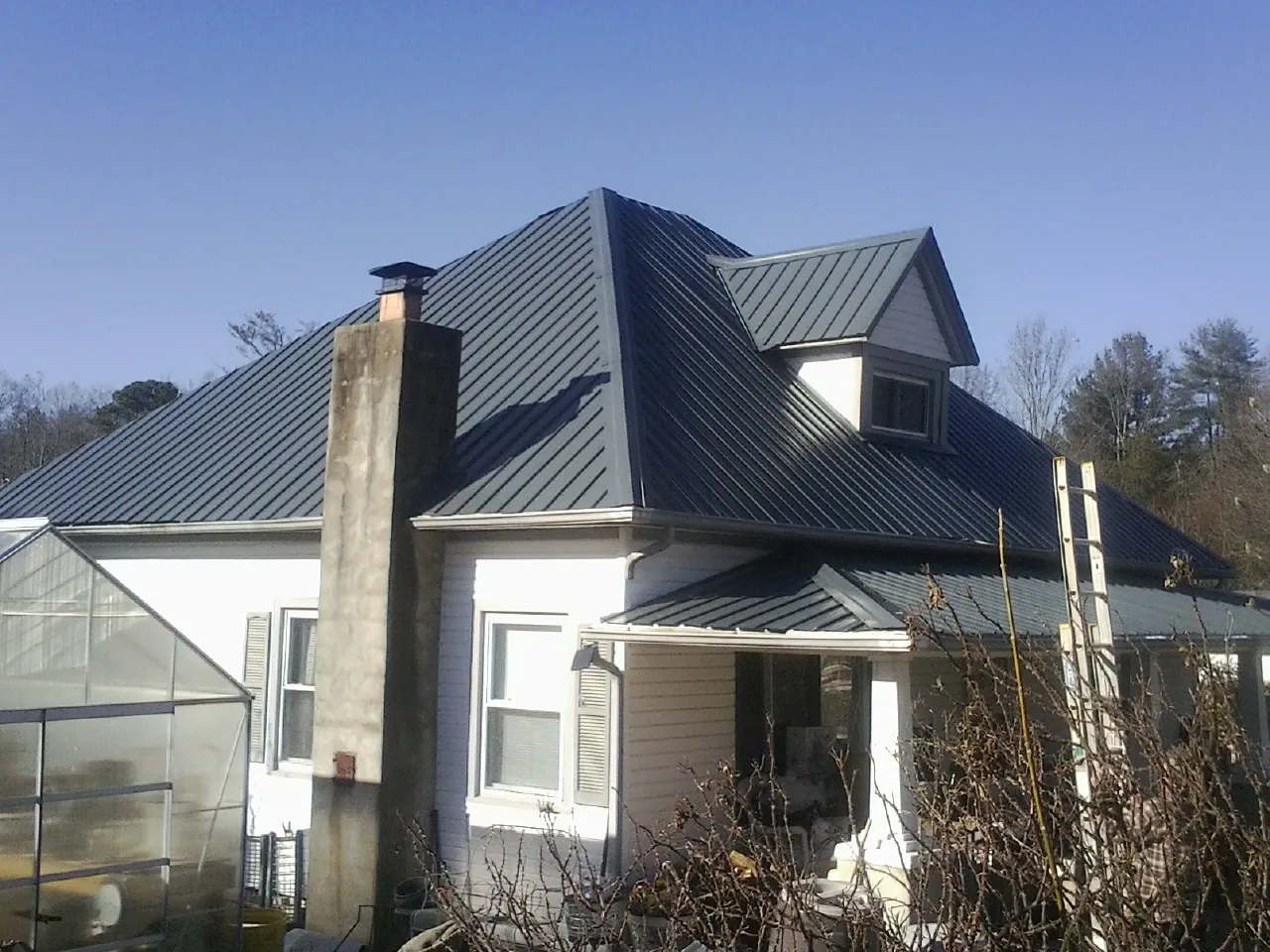 Dark blue standing seam metal roof on a white farmhouse with dormer — Slate & Tile Roof Repair by Roofing Brothers in Avondale Estates