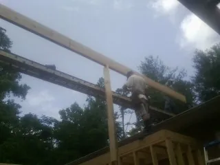 Carpenter setting a ridge beam over a new addition frame — Ice Dam Removal by Roofing Brothers in Avondale Estates