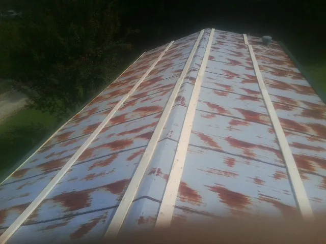 Rusted metal roof panels with new wood purlins before replacement — Storm Damage Roof Repair in Avondale Estates by Roofing Brothers