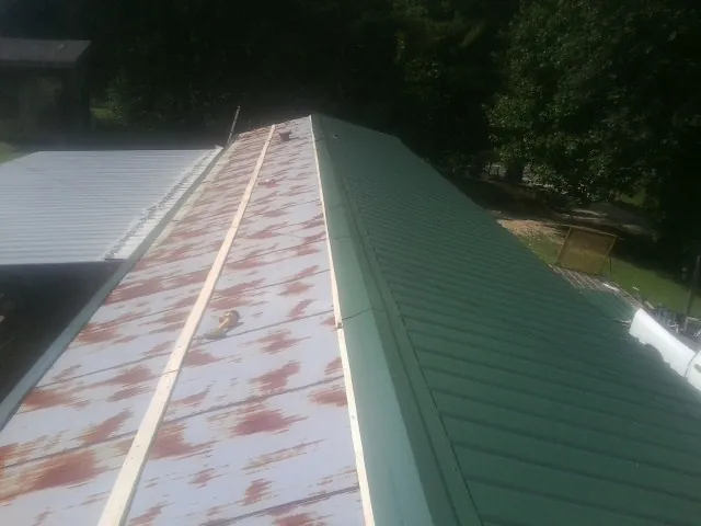Old rusted panels beside newly installed green metal roofing — Wind Damage Roof Repair by Roofing Brothers in Avondale Estates