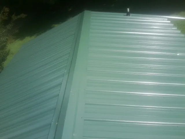 New green metal panels meeting at the ridge of a roof — Flat Roof Repair work by our crew in Avondale Estates