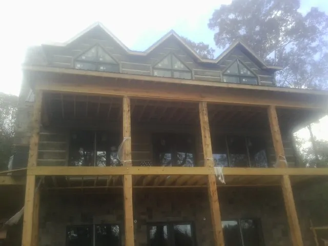 Dormers and porch framing on a large log home under construction — Roof Coating work by our crew in Avondale Estates