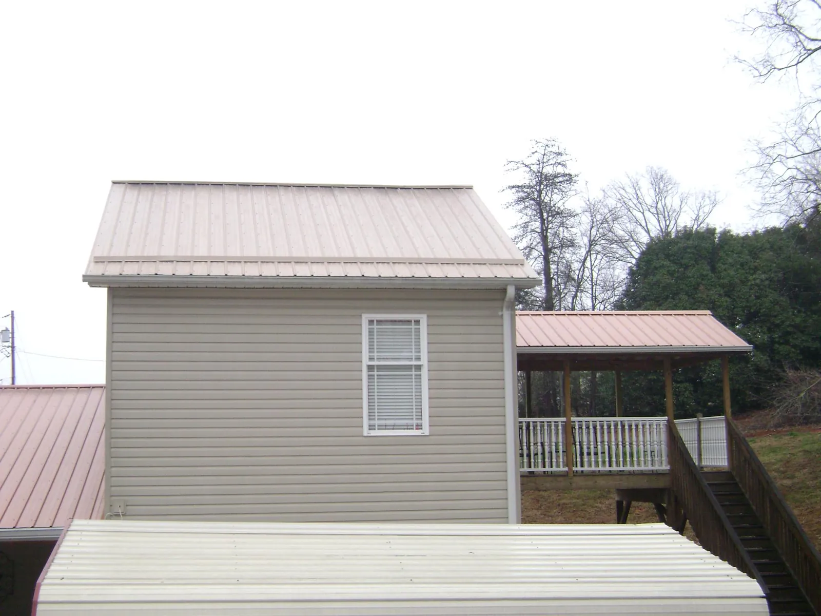 Tan metal roofs on a two story addition and attached porch, from a Roof Replacement job in Avondale Estates