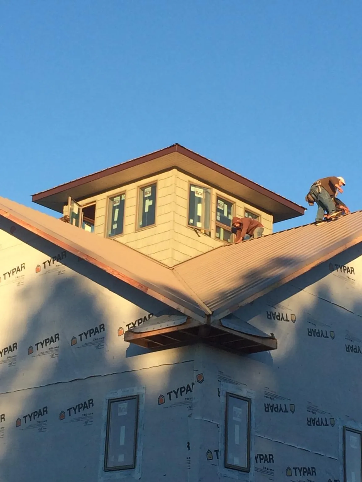 Roofers working around a rooftop cupola on a new metal roof at sunset — Roof Waterproofing in Avondale Estates by Roofing Brothers